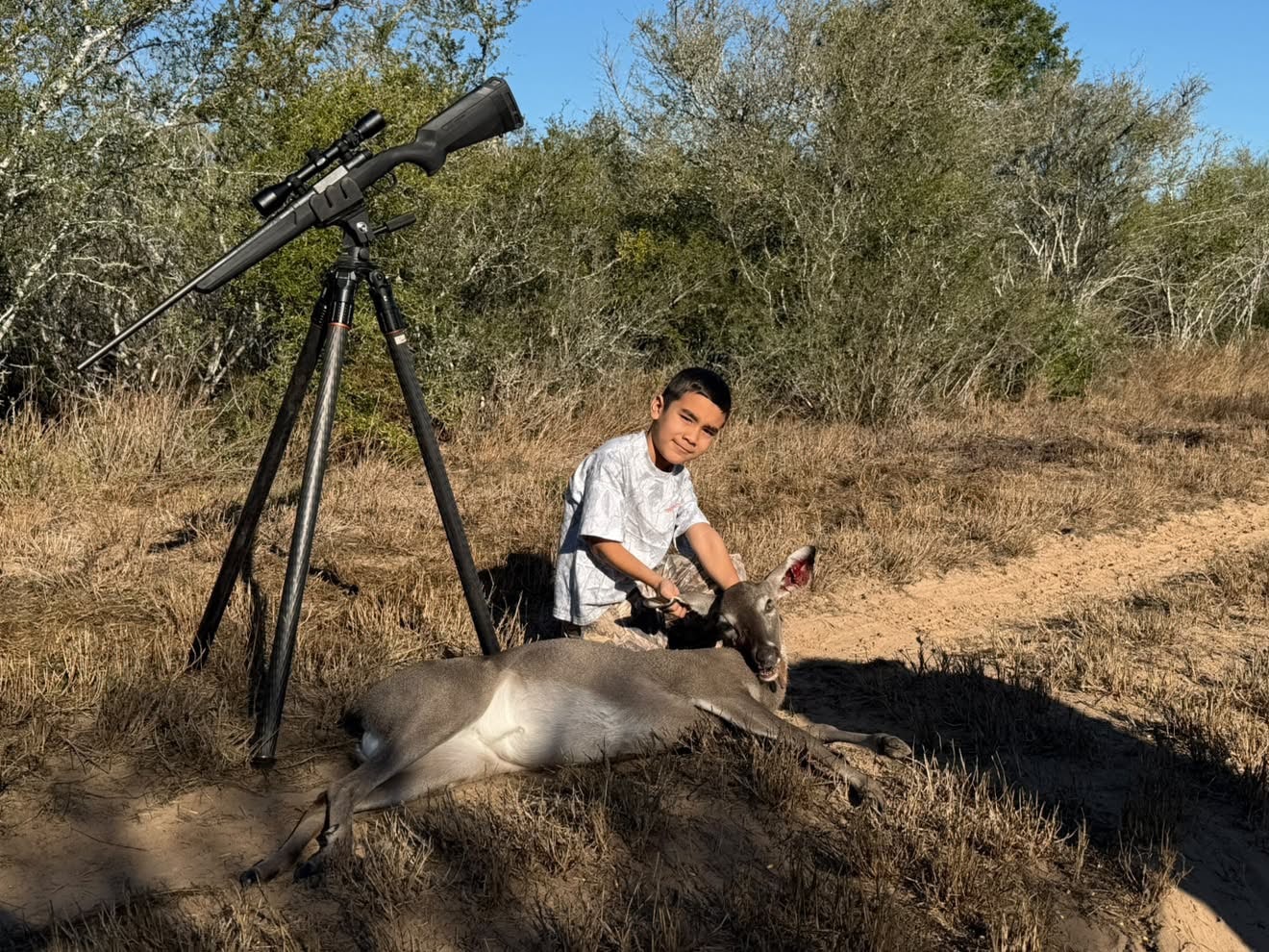 Boy with rifle and harvested deer